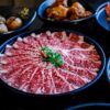 Elegant presentation of thinly sliced Wagyu beef with side dishes, perfect for a gourmet dining experience.