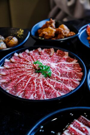 pexels-photo-30195576-30195576 Elegant presentation of thinly sliced Wagyu beef with side dishes, perfect for a gourmet dining experience.