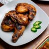 Authentic Indonesian grilled chicken served with fresh green chilies on a traditional plate.